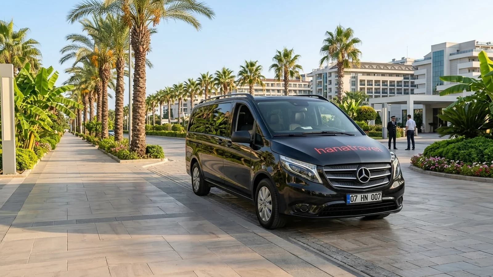 Things to Do From Your Lara Beach Hotel A black transfer van parked on a sunny, palm-lined coastal road behind Lara Beach.